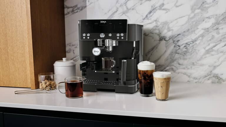 Machine espresso Ninja Luxe Café Premier ES601EUBK noire installée sur un plan de travail avec porte filtre, pichet à lait et moulin intégré visibles