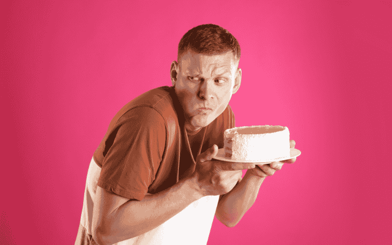 un homme avec un gateau d'anniversaire comme cadeau qui souffle des bougies pour célébrer