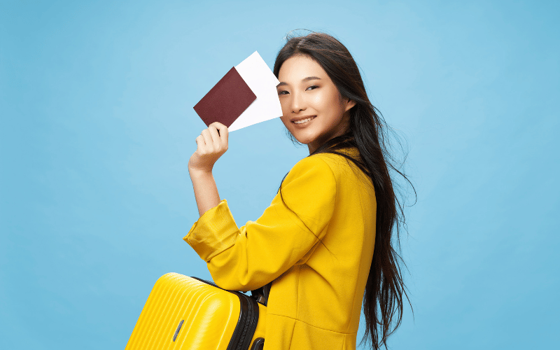 une femme qui a eu comme cadeau d'anniversaire un voyage, elle a un passeport et une valise à la main