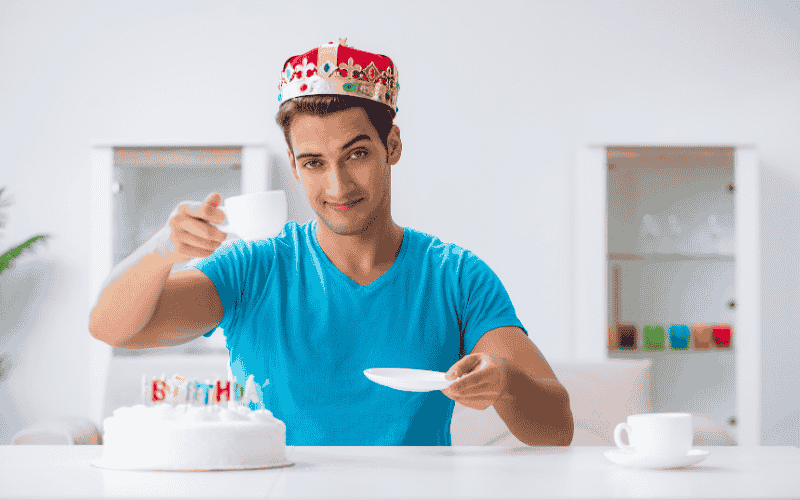 un jeune homme de 20 ans 25 ans 30 ans qui fête son anniversaire avec un gâteau et une couronne