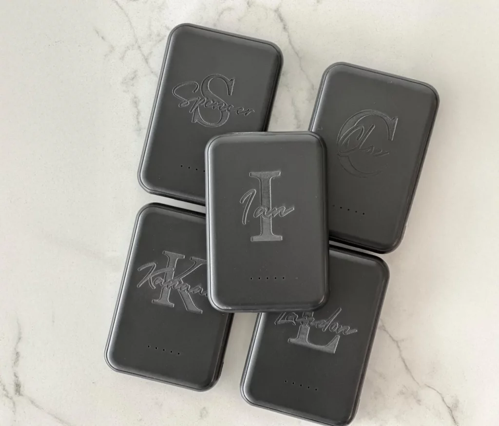 Une batterie externe compacte et colorée posée sur un bureau d’ado, entourée d’un smartphone, d’écouteurs et de stylos, illustrant un accessoire indispensable pour rester connecté toute la journée, même lors des sorties entre amis ou des journées de cours intenses.