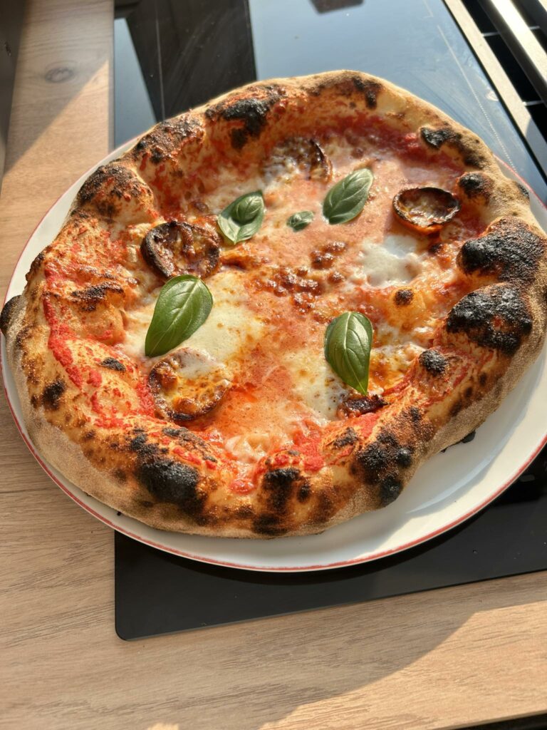 Préparation d’une pâte à pizza maison étalée à la main, juste avant d’être enfournée dans le four Ninja Artisan.
