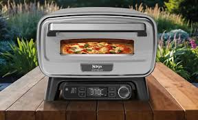 Image du four à pizza électrique Ninja Artisan, conçu pour une utilisation en extérieur, atteignant des températures jusqu'à 700°F (371°C), permettant de cuire des pizzas de style napolitain en seulement 3 minutes. Son design compact et élégant s'intègre parfaitement dans une cuisine extérieure, offrant une cuisson uniforme grâce à sa technologie de contrôle de température complète. Idéal pour les amateurs de pizzas artisanales souhaitant reproduire l'expérience d'une pizzeria à la maison.