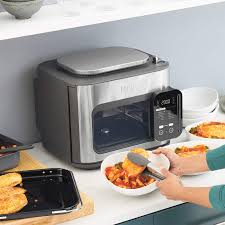 Photographie du multicuiseur Ninja Combi, un appareil tout-en-un combinant les fonctions de four, friteuse à air, cuiseur vapeur et plus encore, avec 14 programmes automatiques. Son design moderne en acier inoxydable s'adapte à toutes les cuisines, offrant une solution polyvalente pour préparer des repas complets rapidement et facilement. Parfait pour les familles recherchant un appareil multifonction pour simplifier la préparation des repas