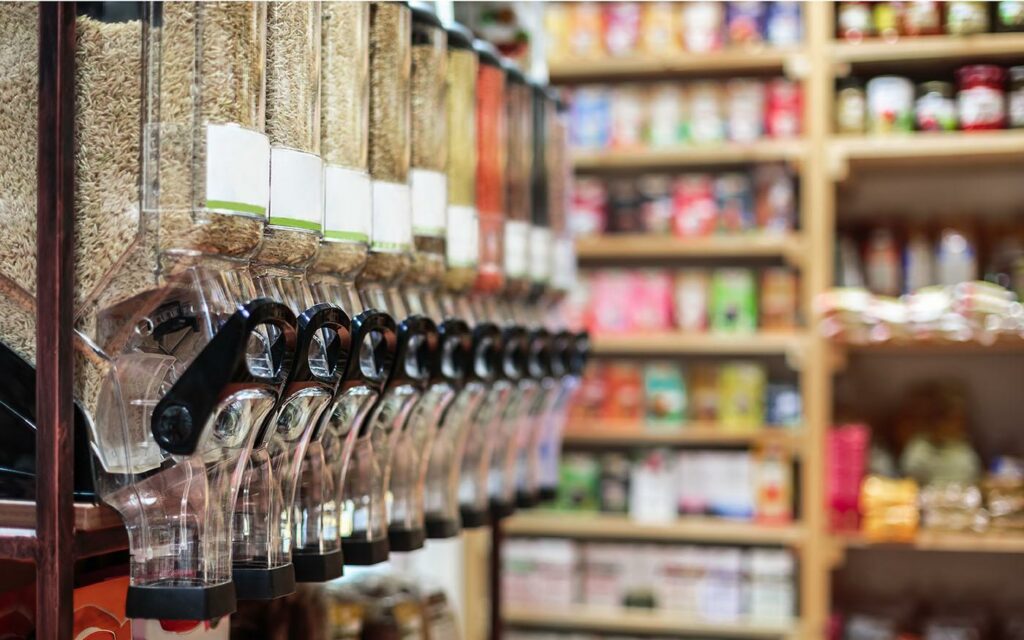 Fruits et légumes bio, œufs fermiers et pain artisanal sur les étals d’un magasin bio de quartier, produits ultra-frais difficilement remplaçables en ligne