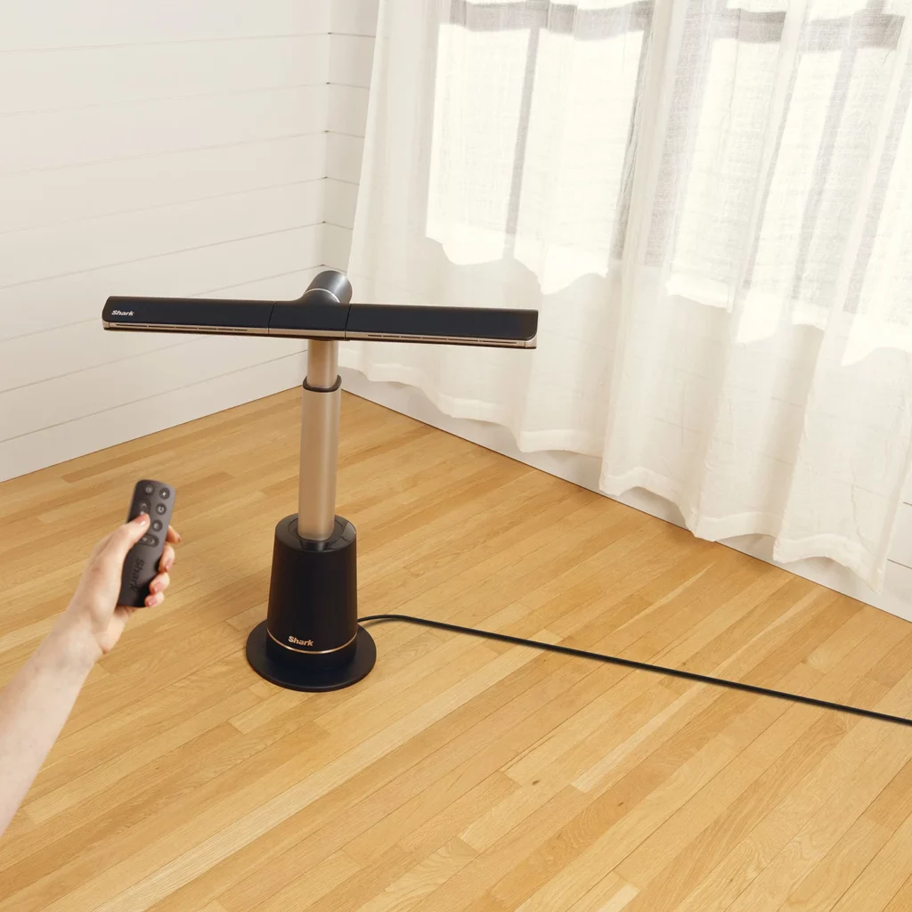  photo rapprochée d’un ventilateur Shark TurboBlade TF200SEU en fonctionnement dans un salon élégant avec des plantes vertes en arrière-plan, illustrant le design moderne et la puissance de l’air diffusé par le ventilateur sans pale, parfait pour un usage en intérieur et offrant une solution de rafraîchissement puissante et silencieuse