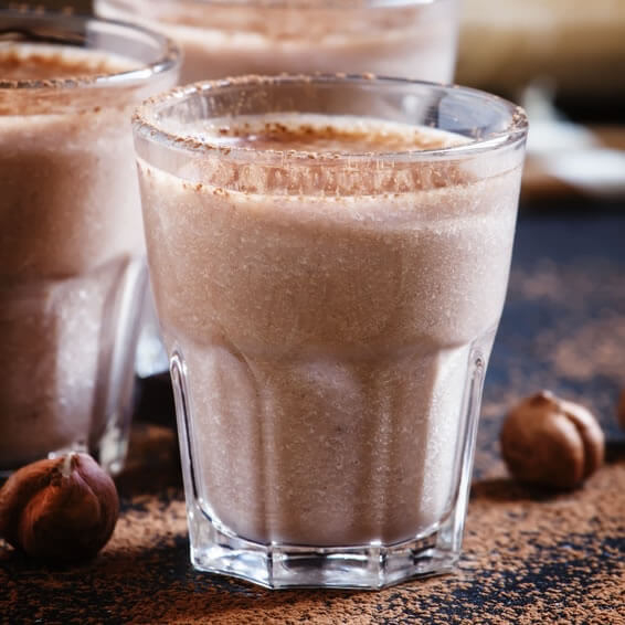 Milkshake maison à base de Nocciolata Bianca, lait et sucre, préparé avec le Ninja Slushi en mode Milkshake, texture ultra crémeuse et mousseuse, servi dans un grand verre avec paille, boisson glacée et gourmande à la noisette blanche, recette facile à faire à la maison sans blender, parfait pour les amateurs de douceurs régressives