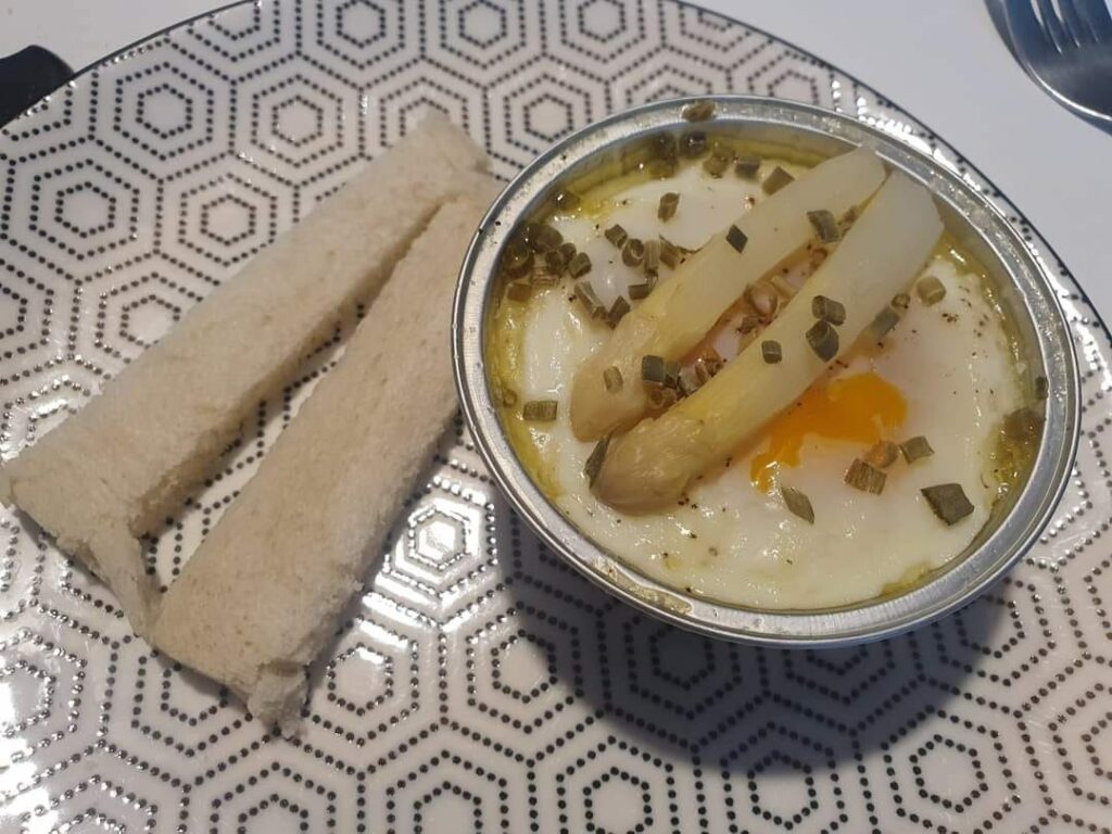 Œufs cocotte aux asperges réalisés dans le Ninja Combi, cuits à la vapeur puis dorés au four en mode Bake, servis dans des cocottes individuelles, garnis de pointes d’asperges vertes ou blanches, crème au parmesan et ciboulette fraîche, plat printanier léger et raffiné, avec option pain de mie toasté et fromage gratiné pour plus de gourmandise, recette idéale pour brunch ou entrée de saison