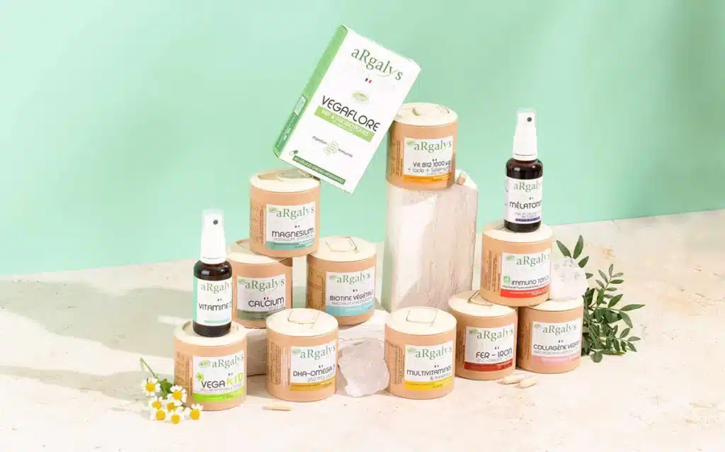 Flacons de compléments alimentaires Argalis posés près de plantes séchées, symbolisant la naturalité des formules, les gélules végétales et la simplicité efficace qui caractérisent la marque.