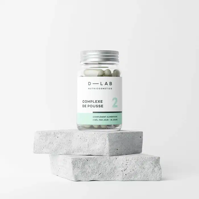 Boîte Complexe de Pousse D LAB posée sur une table en bois, complément alimentaire riche en acides aminés et biotine que j’ai utilisé pour stimuler la pousse des cheveux et renforcer mes ongles