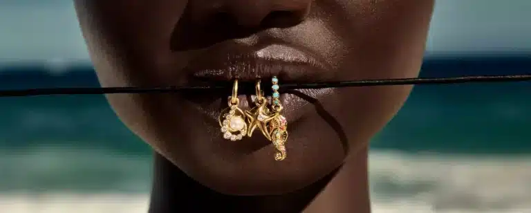 Femme portant un bracelet Pandora avec plusieurs charms en argent et en or, souriante, représentant l’attachement émotionnel que les clientes peuvent avoir à leurs bijoux Pandora, très populaire en France pour ses charms personnalisables, bagues fines et colliers symboliques.