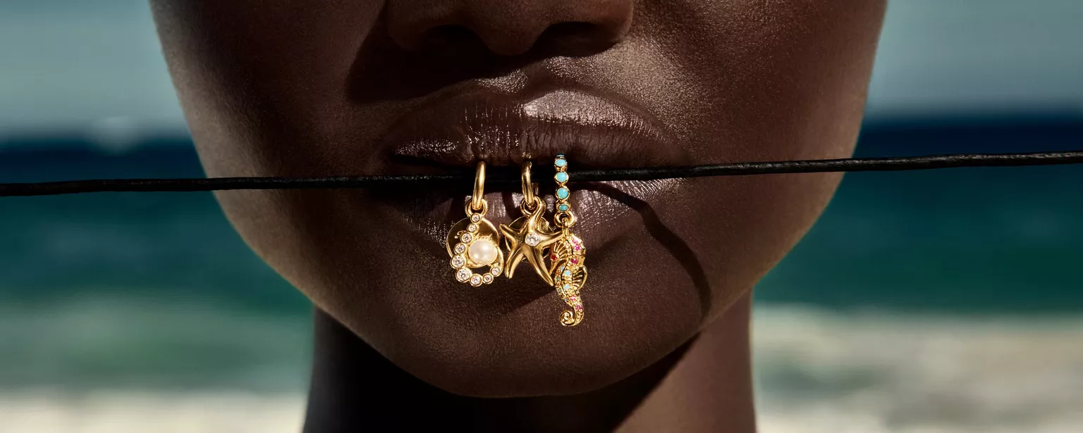 Femme portant un bracelet Pandora avec plusieurs charms en argent et en or, souriante, représentant l’attachement émotionnel que les clientes peuvent avoir à leurs bijoux Pandora, très populaire en France pour ses charms personnalisables, bagues fines et colliers symboliques.