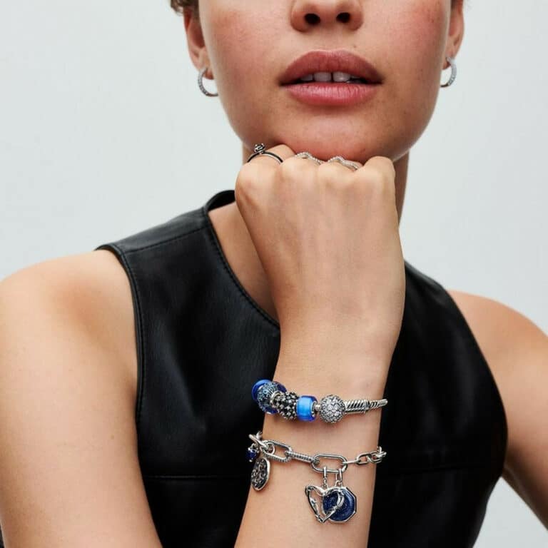 Bracelet Pandora avec plusieurs charms en argent et or rose, porté au poignet d’une femme élégante