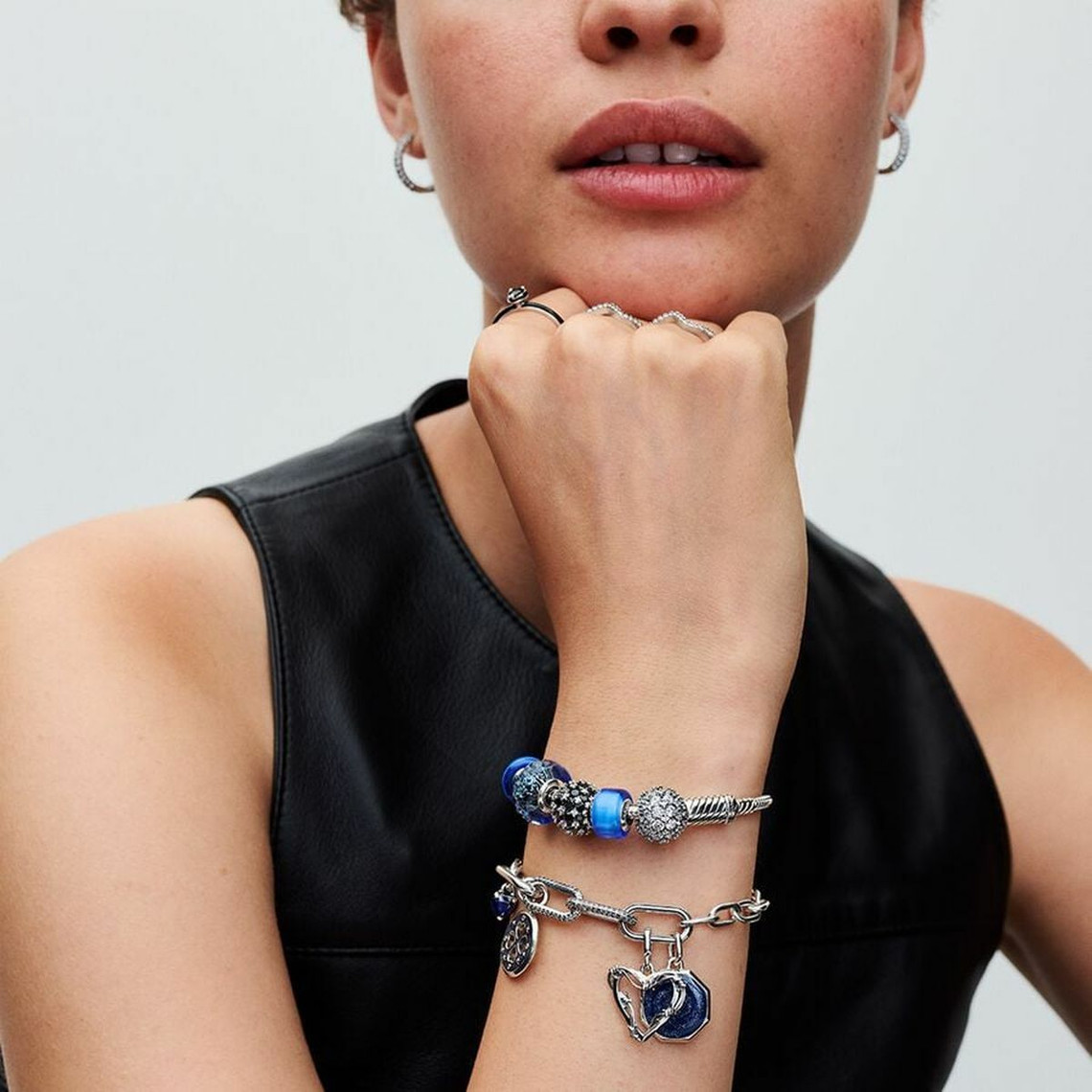 Bracelet Pandora avec plusieurs charms en argent et or rose, porté au poignet d’une femme élégante