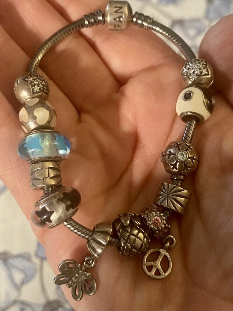  Différents modèles de bracelets Pandora exposés avec un large choix de charms en arrière-plan
