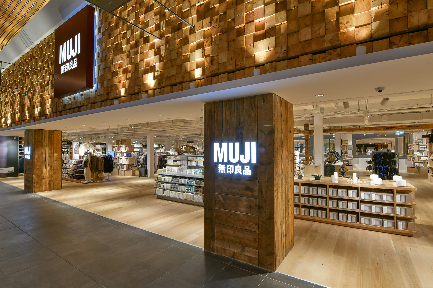 Vue intérieure d’un magasin Muji à Paris avec ses étagères en bois clair, ses vêtements minimalistes et ses rangements empilables, dans une ambiance zen et épurée qui reflète bien l’univers de la marque Muji France.
