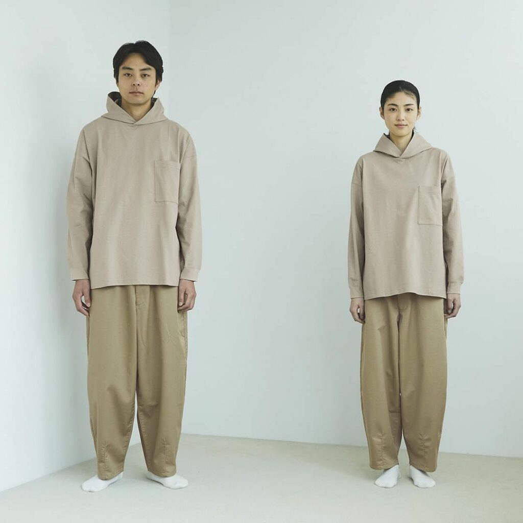 Sélection de vêtements Muji en coton bio, dont un pyjama posé sur un lit clair, avec des coupes amples et des couleurs neutres, illustrant la sobriété et le confort des vêtements proposés par Muji en France.