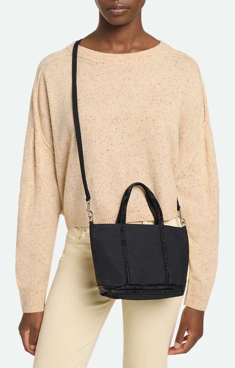 Photographie en gros plan du cabas Vanessa Bruno dans sa version classique en lin naturel avec anses et bande en paillettes dorées, posé sur un banc en bois, parfaite illustration de ce sac iconique de la marque française, très recherché pour son style bohème chic et sa fabrication de qualité, emblème de la mode parisienne et accessoire phare dans les collections de Vanessa Bruno France, décliné en plusieurs tailles et matières comme le lin, le cuir ou le velours.