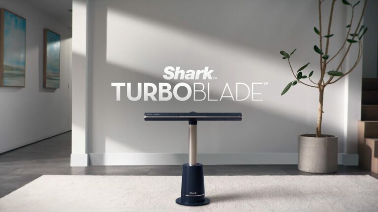 Photographie du ventilateur Shark TurboBlade, un modèle sans pales à haute vitesse, élégant et moderne, posé dans un salon contemporain, illustrant parfaitement le design épuré de ce ventilateur Shark. Ce visuel met en valeur les dimensions élancées de la version XL du Shark TurboBlade fan, apprécié pour sa puissance, son fonctionnement silencieux et sa diffusion d'air uniforme. Idéal pour illustrer un avis sur le Shark TurboBlade, ce visuel rappelle aussi qu’il est disponible en France, notamment chez Boulanger, Costco ou sur le site officiel de Shark Europe. On aperçoit à l’arrière une télécommande, rappelant les fonctionnalités pratiques du ventilateur Shark TurboBlade France, parfait pour ceux qui recherchent une alternative esthétique et efficace aux ventilateurs traditionnels.