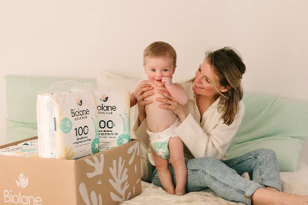 Paquet de couches Biolane taille 4 posé sur un pyjama bébé, illustrant l’efficacité anti-fuites et l’absorption nocturne des couches Biolane, avec avis sur la tenue pendant 12 heures, même chez les bébés très actifs.