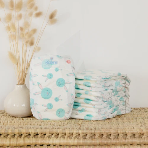 Couches Biolane posées à côté d’un tote bag réutilisable, représentant les engagements environnementaux de la marque, l’utilisation de cellulose certifiée FSC et l’absence de suremballage plastique dans la fabrication de ses couches bébé.