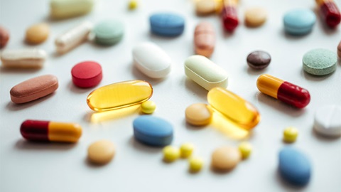 Photo montrant des gélules de compléments alimentaires en vrac sur une table de laboratoire, illustrant l’opacité de leur fabrication.