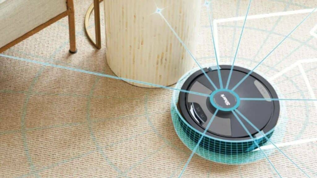 gros plan sur un aspirateur robot Shark en train d’aspirer des miettes sur un sol clair pour illustrer la qualité de fabrication et d’aspiration