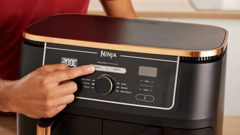 Photo du Ninja Foodi MAX AF400EU posé sur un plan de travail de cuisine avec ses deux tiroirs ouverts, l’un rempli de frites croustillantes et l’autre d’un poulet rôti, illustrant sa capacité de 9,5 L, sa technologie DualZone et ses 6 modes de cuisson (Air Fry, Max Crisp, Roast, Bake, Reheat et Dehydrate).