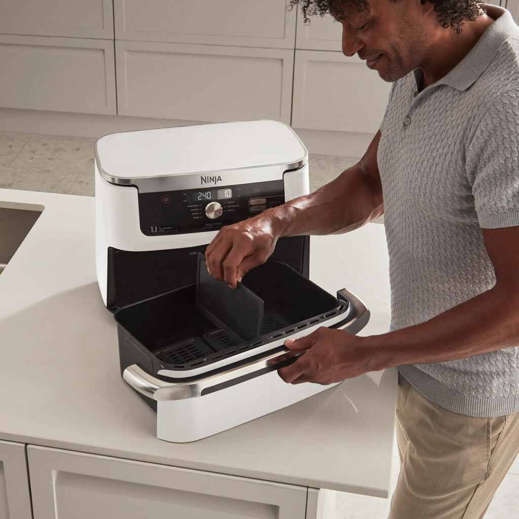 Le Ninja Foodi Flex 7-en-1 AF500EU avec un gigot d’agneau entier de 2 kg accompagné de légumes rôtis dans sa cuve de 10,4 litres, démontrant sa capacité XXL pour cuisiner pour 8 personnes ou plus.