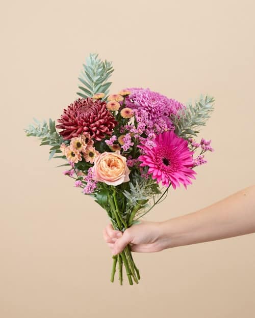 Idée cadeau d’anniversaire floral : abonnement Bergamotte avec bouquets de fleurs fraîches livrés chaque mois, posés dans un vase sur une table en bois clair, ambiance lumineuse et naturelle, évoquant un cadeau poétique et raffiné qui se renouvelle au fil des saisons.