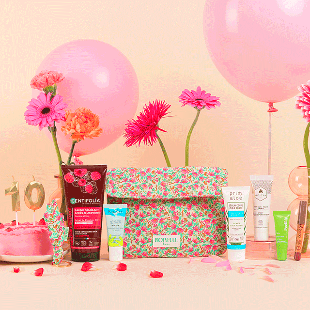 Idée cadeau anniversaire pour femme : box beauté naturelle Biotyfull Box contenant soins visage, maquillage, parfums et produits capillaires bio, posée sur une table en bois clair entourée de fleurs séchées, ambiance douce et lumineuse, évoquant une routine beauté naturelle et relaxante, parfaite pour offrir à sa mère, sa sœur ou une amie passionnée de cosmétiques clean.