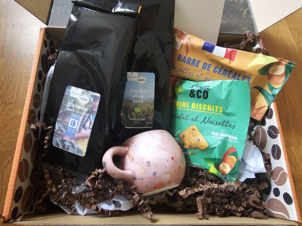 Idée cadeau d’anniversaire pour amateur de café : box Mon Rituel Café avec sachets de cafés torréfiés, tasse et moulin posés sur une table, ambiance chaleureuse et gourmande, lumière naturelle évoquant le plaisir du café du matin.