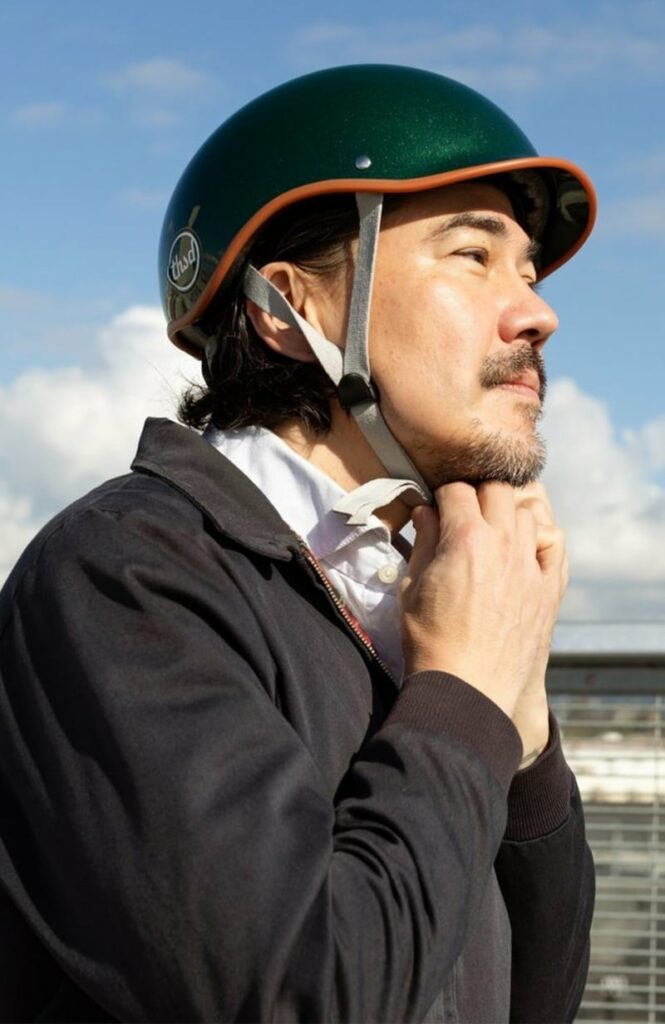  Idée cadeau anniversaire sport : casque de vélo Thousand réglable et ventilé, posé sur un vélo vintage, ambiance urbaine et élégante, lumière naturelle, objet design et sécuritaire pour les amateurs de balades à vélo.