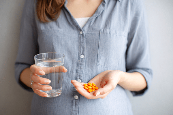 Flacons de compléments alimentaires naturels et probiotiques féminins posés sur une table en bois, illustrant le soutien intérieur pour la flore intime et le cycle hormonal.