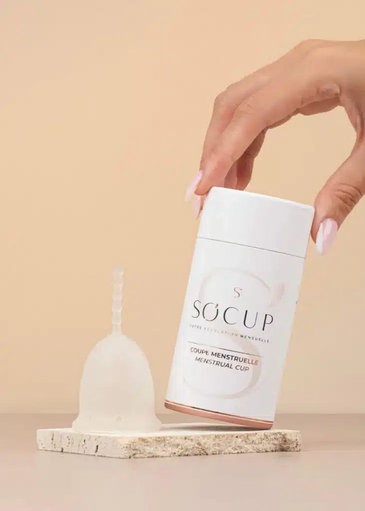 Coffret So’Cup comprenant une coupe menstruelle en silicone platine et un stérilisateur pliable, photographié sur un fond doux, représentant une solution pratique et accessible pour débutantes dans mon avis comparatif.