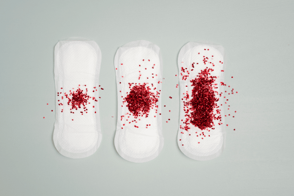 Trois culottes menstruelles alignées sur un lit clair, représentant les repères concrets selon flux léger, normal ou abondant, avec conseils sur le nombre de modèles nécessaires.
