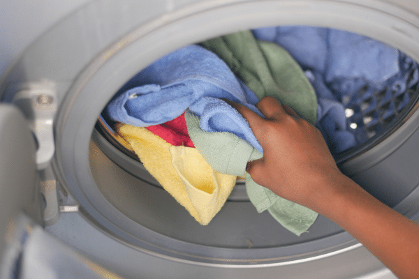 Culotte menstruelle posée à côté d’un sèche-linge barré d’une croix rouge, image symbolique pour rappeler les erreurs à éviter comme l’eau chaude, l’adoucissant ou le séchage haute température.