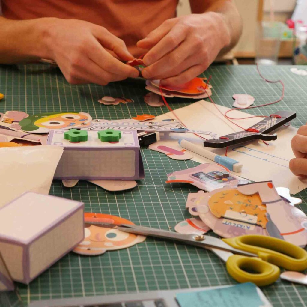 Idée cadeau anniversaire pour enfant : box Pandacraft avec activité manuelle et magazine éducatif sur les volcans, la nature ou les sciences, posée sur une table colorée avec ciseaux, colle et papiers, ambiance lumineuse et ludique évoquant la découverte, la créativité et le plaisir d’apprendre en s’amusant.