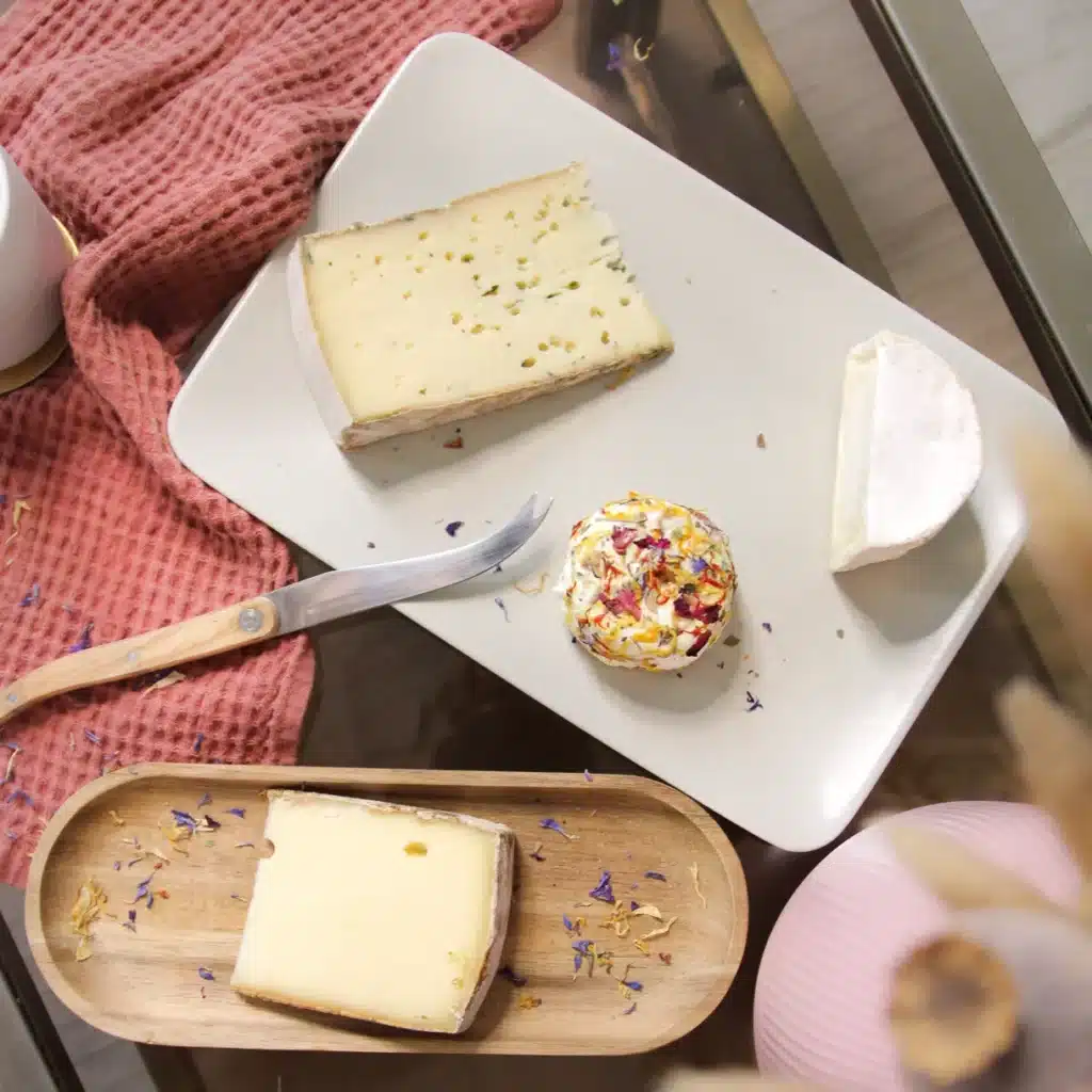 Idée cadeau anniversaire pour amateur de fromages : coffret La Box Fromage contenant quatre fromages artisanaux de saison soigneusement emballés, posés sur une planche
