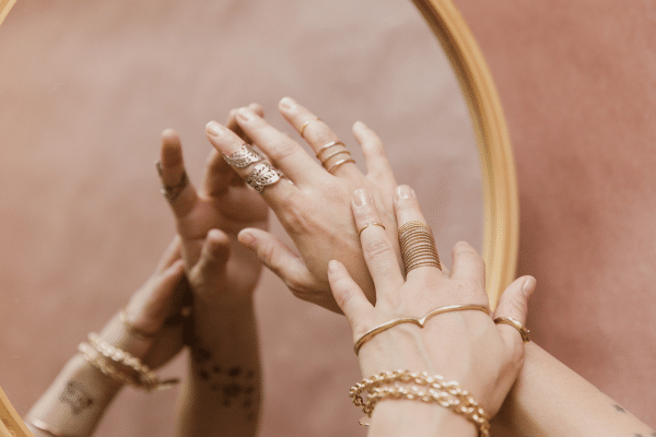 photo de plusieurs bijoux fins posés sur une table en bois clair, mélange de bagues, bracelets et colliers pour illustrer un comparatif de marques de bijoux