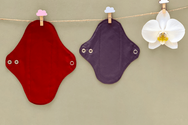 Serviettes hygiéniques lavables en tissu coloré, fixées par boutons pression, protection menstruelle réutilisable, écologique et économique sur plusieurs années.