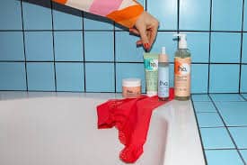 Gel lavant intime, huile corporelle et compléments alimentaires Jho disposés sur un plateau, illustrant la gamme bien-être féminine naturelle.