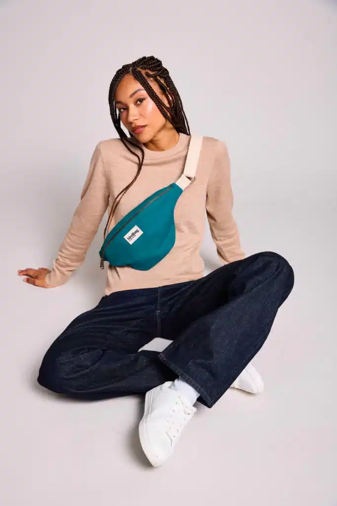 Banane Hindbag couleur safran portée en bandoulière, vue de près sur la toile épaisse, volume compact mais généreux, ouverture large, sangle réglable, accessoire emblématique de la marque, choix de couleurs variées, présentation idéale pour illustrer un avis détaillé sur la banane Hindbag.