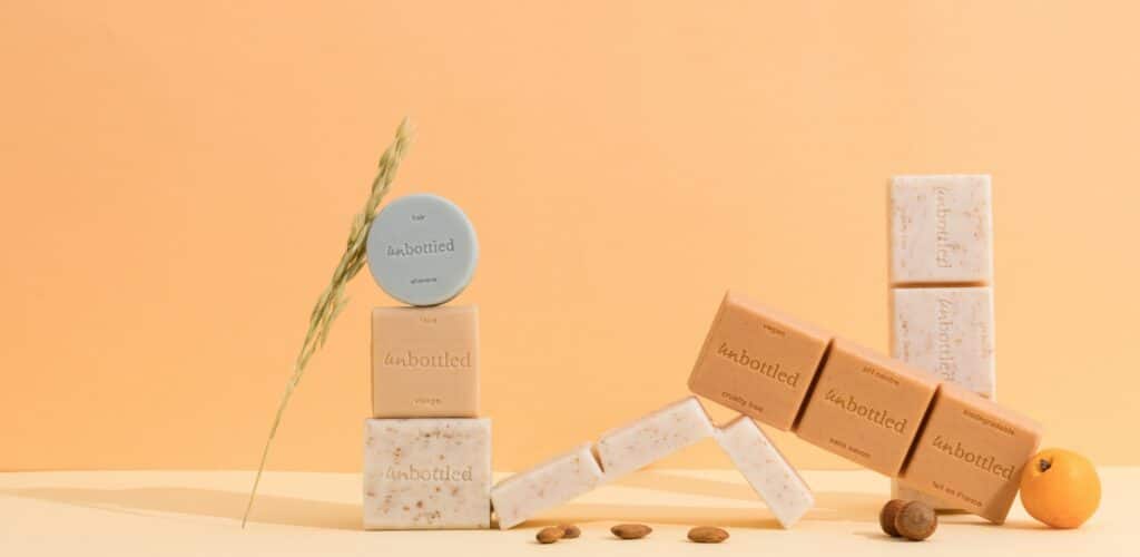 Produits cosmétiques solides Unbottled présentés dans une salle de bain, shampoing solide, gel douche sans bouteille et déodorant naturel