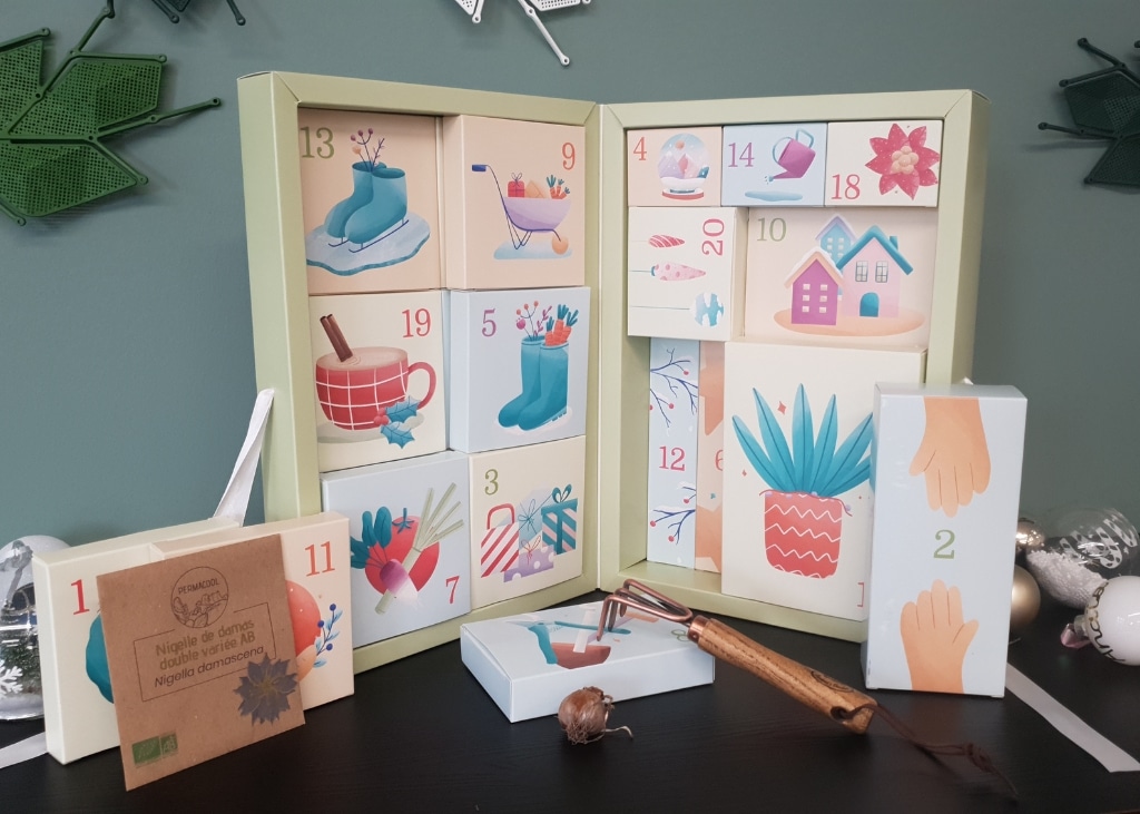Calendrier de l’Avent Permacool sous forme de livre géant avec sachets de graines bio, outils et accessoires décoratifs destinés au jardinage hivernal.