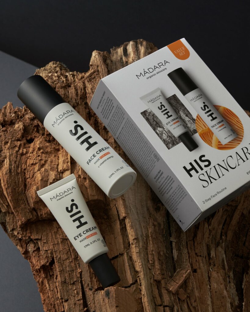 Idée cadeau d’anniversaire beauté naturelle : coffret Mádara avec crèmes et soins visage bio, flacons épurés posés sur une table en bois, fleurs blanches à côté, ambiance lumineuse et nordique évoquant une routine de soin minimaliste et apaisante.