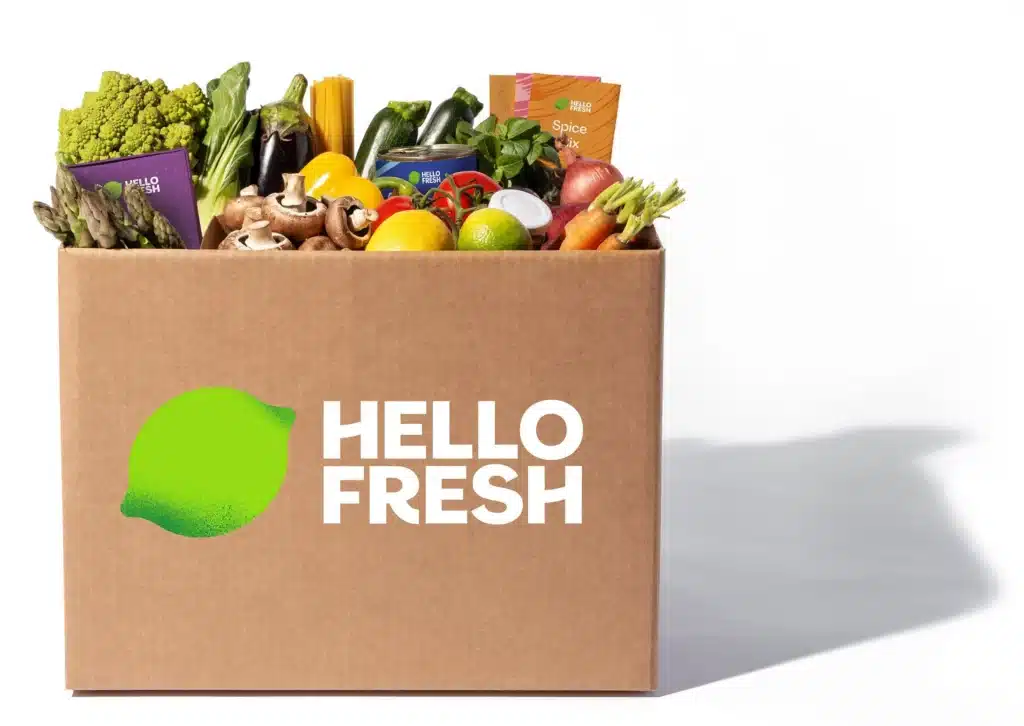 Box HelloFresh ouverte avec ingrédients frais, légumes, herbes et fiches recettes claires pour préparer facilement un repas maison équilibré.