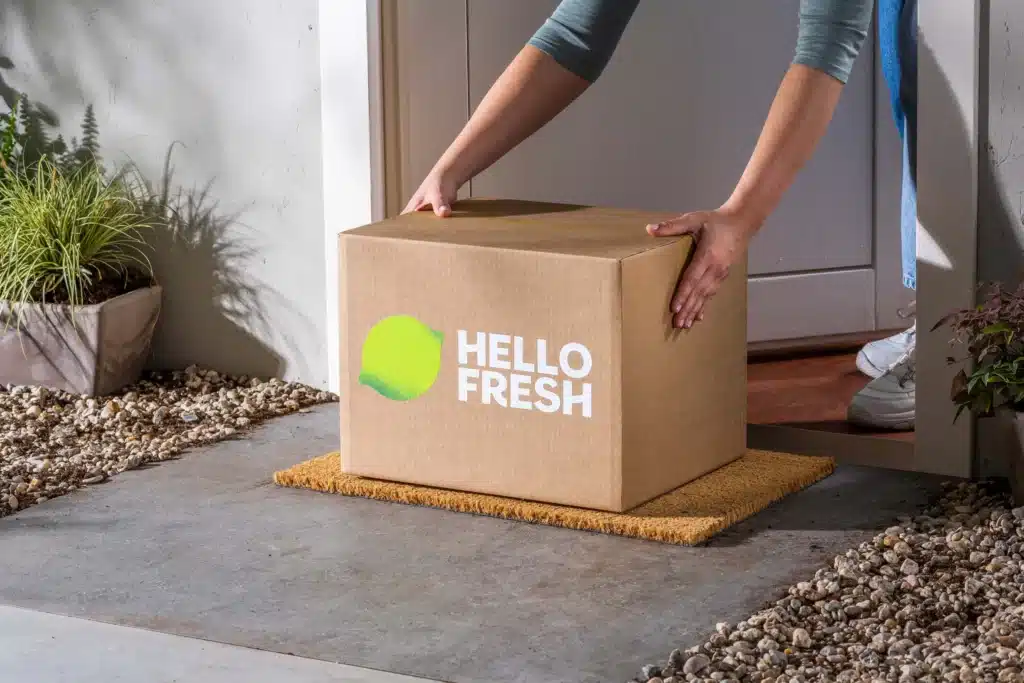 Capture d’une box HelloFresh avec ingrédients triés et calcul du prix par portion affiché sur une fiche recette colorée.