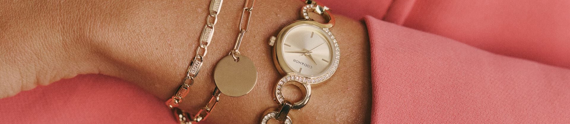 Présentation de bijoux Histoire d’Or dans une vitrine lumineuse : bagues, colliers et montres en or, argent et plaqué or exposés dans un décor sobre.