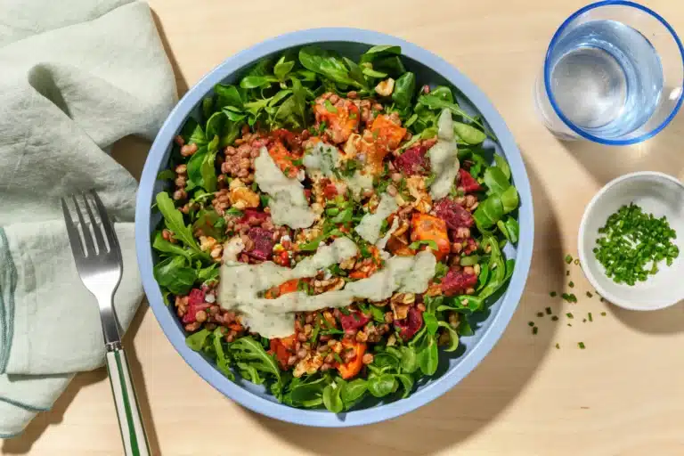 Box HelloFresh France posée sur un plan de travail de cuisine avec ingrédients frais, légumes colorés, fiches recettes et panier repas prêt à cuisiner.